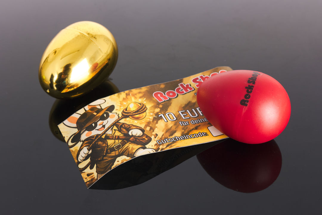 Rock Shop Egg-Shaker, goldenes Ei und 10 Euro Einkaufsgutschein auf spiegelndem Untergrund