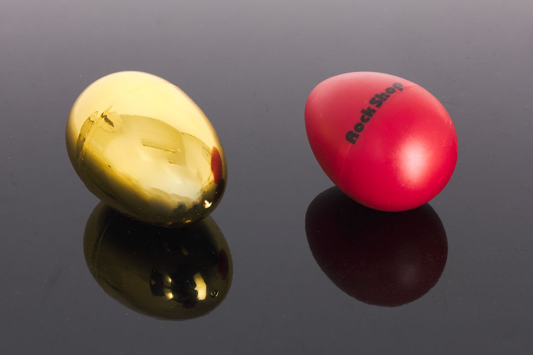 Roter Rock Shop Egg-Shaker und goldenes Ei auf spiegelndem Untergrund
